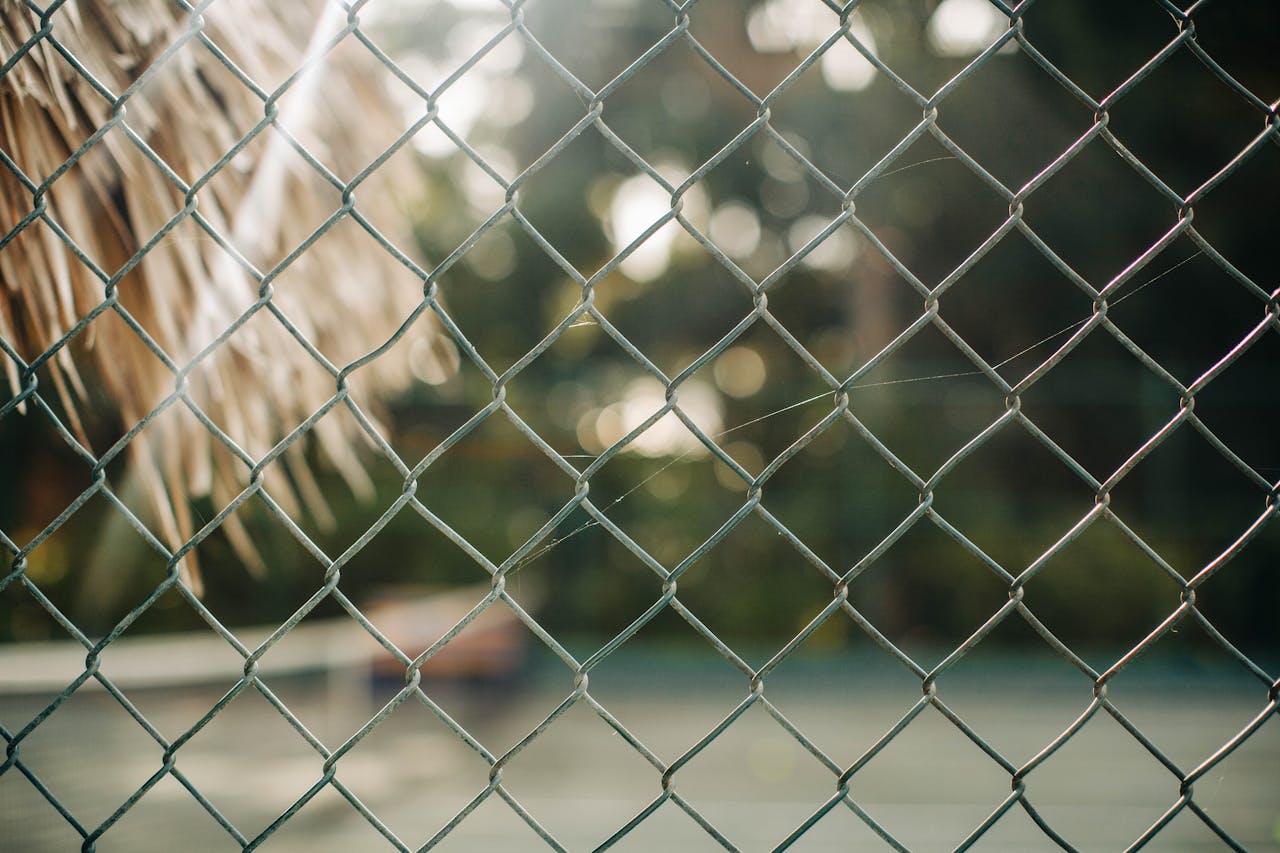 Detailed view of a chain link fence against a blurred outdoor backdrop.