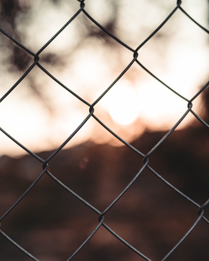 Close-up of a metal chain fence with a sunset backdrop in Barcelona.